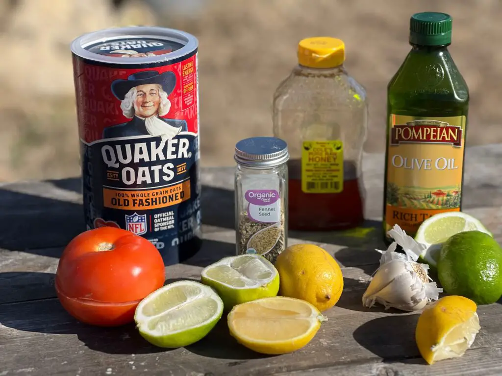 On a wooden table rests a tomato, lime, lemon, olive oil, honey, garlic, and quaker oats!