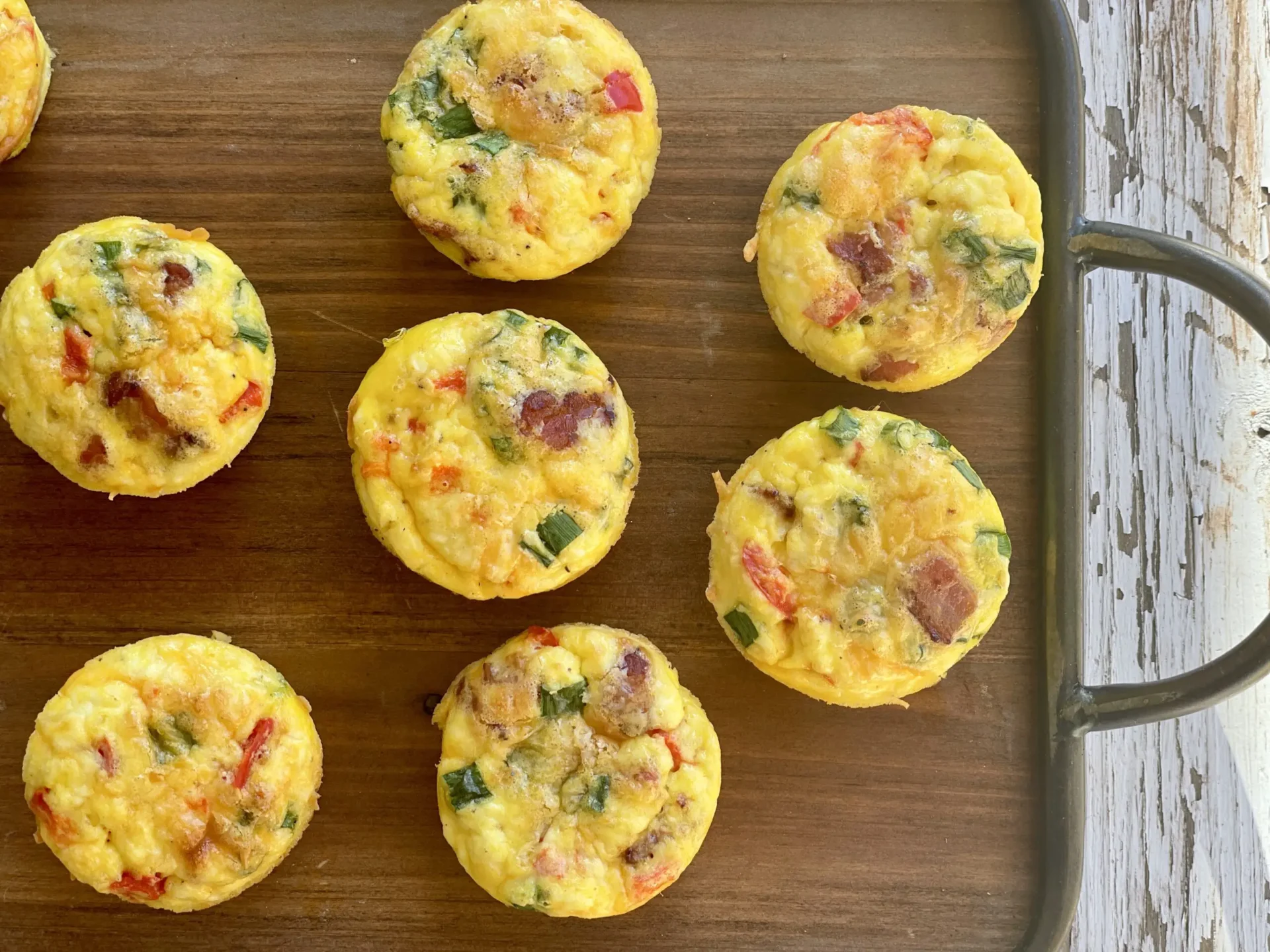 A tray of mini quiches with ham and peppers.