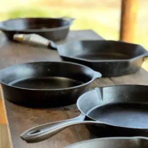 A table with several cast iron pans on it.