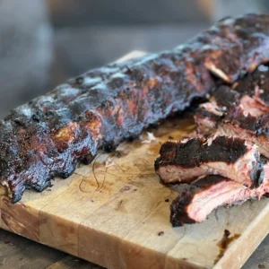 A slab of meat on top of a wooden cutting board.