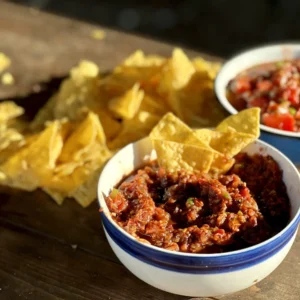 A bowl of chili next to some tortilla chips.