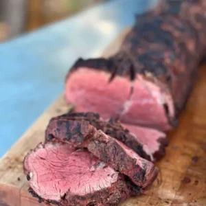 Grilled and sliced beef tenderloin on a cutting board.