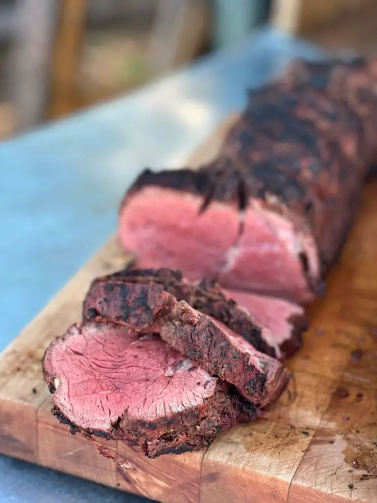 Grilled and sliced beef tenderloin on a cutting board.