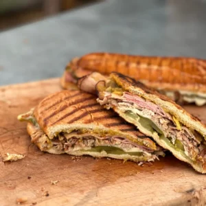 A cut in half sandwich sitting on top of a wooden cutting board.