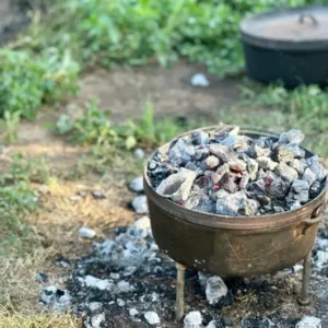 Dutch oven with hot coals on a tripod.