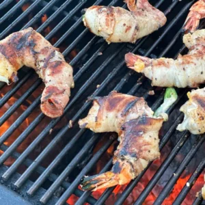 Bacon-wrapped shrimp grilling on a grill.