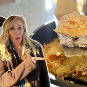 A woman pointing to an open sandwich on top of a table.