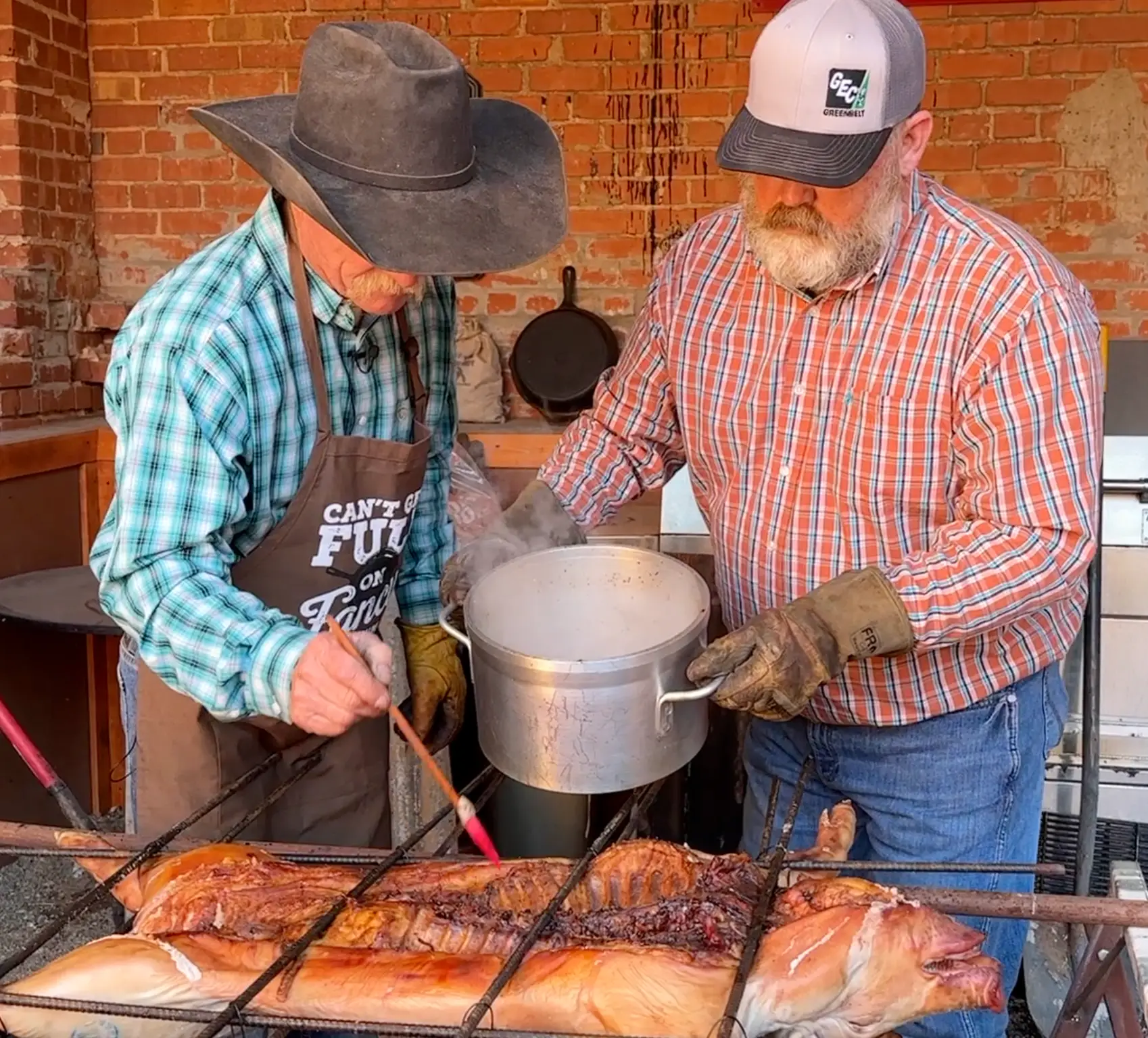 Two men cooking fish on a grill.