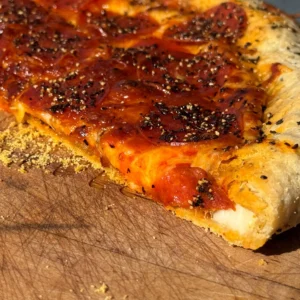 A piece of pizza sitting on top of a wooden board.