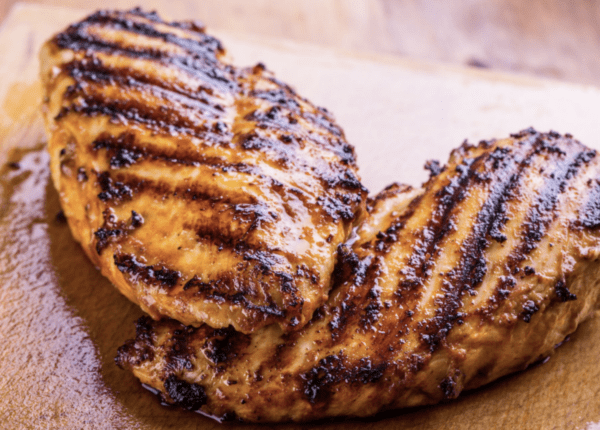 Grilled chicken breast on a cutting board.