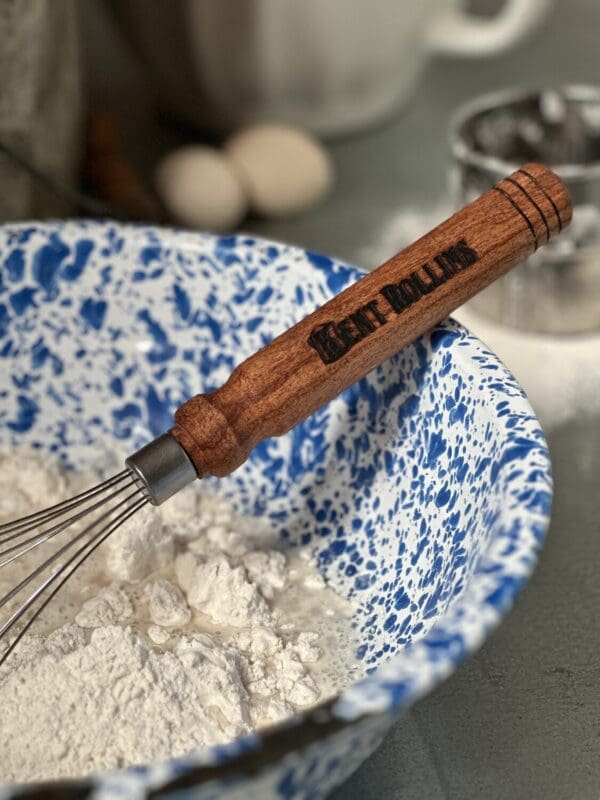 Wooden whisk in a mixing bowl of flour.