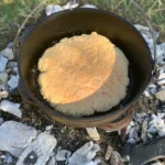 A pot sitting on top of the ground with food inside.