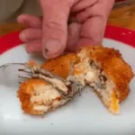 A person holding a fork over a piece of food.