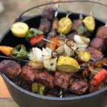 A bowl of food with meat and vegetables on it.