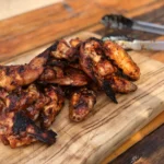 A wooden cutting board with some chicken on it