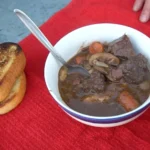 A bowl of stew and bread on the table.