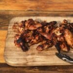 A wooden cutting board with some chicken on it