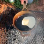 A person is cooking food in an outdoor grill.