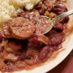 A plate of food with beans and sausage.