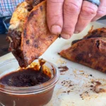 A person dipping some food into sauce