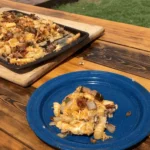 A blue plate with food on it next to an open air oven.