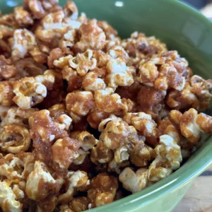 A green bowl filled with caramel popcorn.