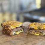 A sandwich cut in half on top of a wooden board.