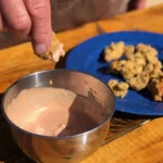 A person dipping food into some milk