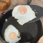 Two eggs are fried in a pan on the stove.