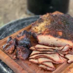 A wooden cutting board with some meat on it