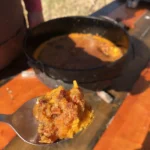 A spoon and some food on top of a table.