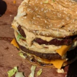 A large hamburger with cheese and lettuce on top of it.