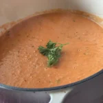 A pot of soup with some green leaves in it