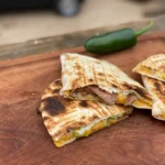 A close up of some quesadilla on a wooden board