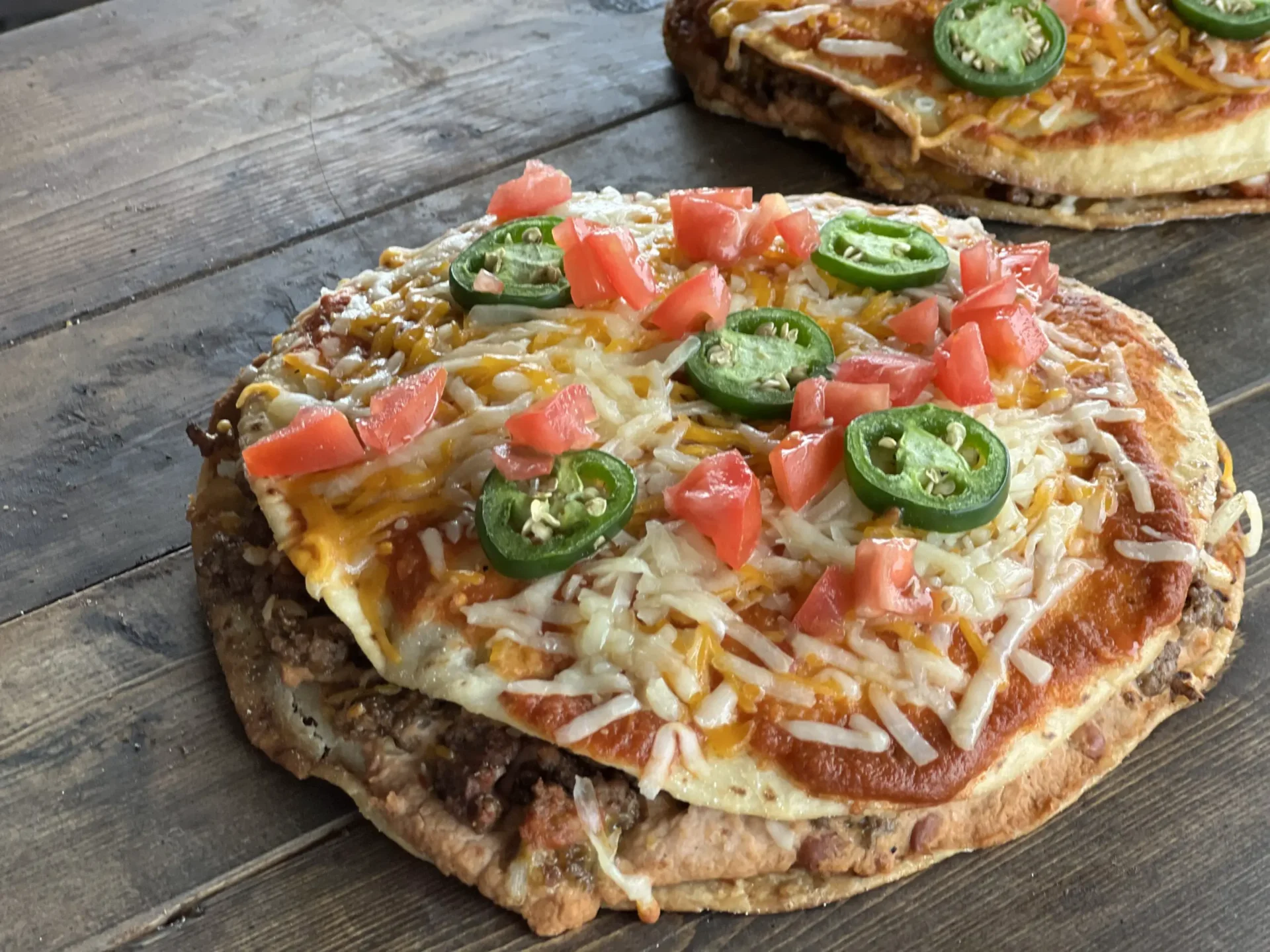 A pizza with cheese, tomatoes and jalapenos on it.