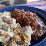 A blue bowl of food with beans and potatoes.