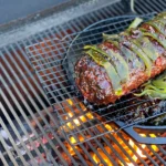 A meat on the grill with some green peppers