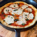 A pizza with cheese and basil in a pan.