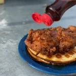 A person is pouring ketchup on some food