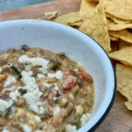 A bowl of food next to some tortilla chips.