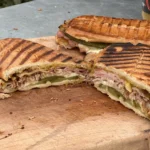 A cut in half sandwich sitting on top of a wooden board.