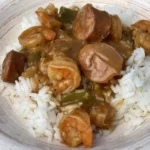 A bowl of rice and shrimp with sauce.