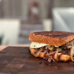 A sandwich sitting on top of a wooden cutting board.