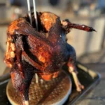 A close up of a chicken on top of a waffle