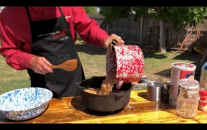 A person pouring sauce into a pot on top of a table.