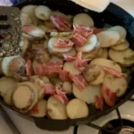 A pan of food with potatoes and bacon in it.