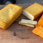 A wooden table topped with cheese and crackers.