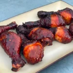 A plate of chicken and ribs on top of a table.