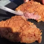 A person cutting into some meat on top of a table.