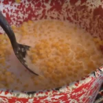 A bowl of corn and milk with a fork.